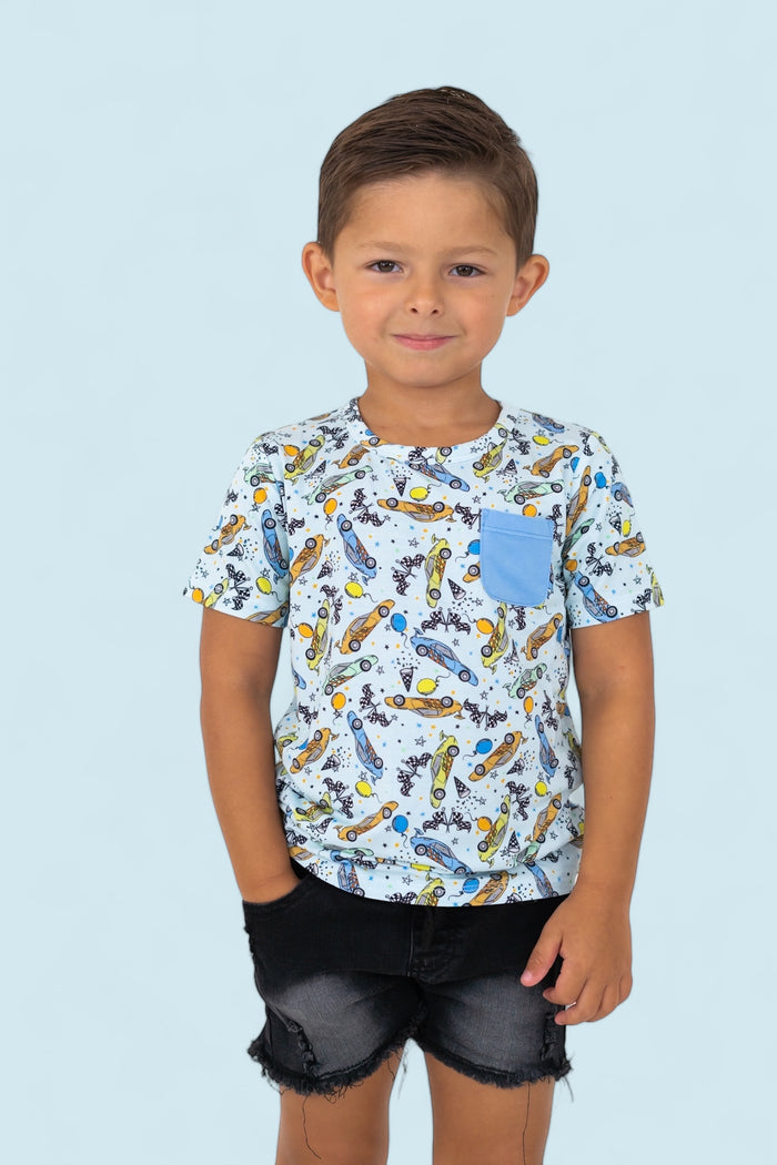 Boy wearing light blue t-shirt with racing car and planet print, blue chest pocket, paired with black denim shorts.