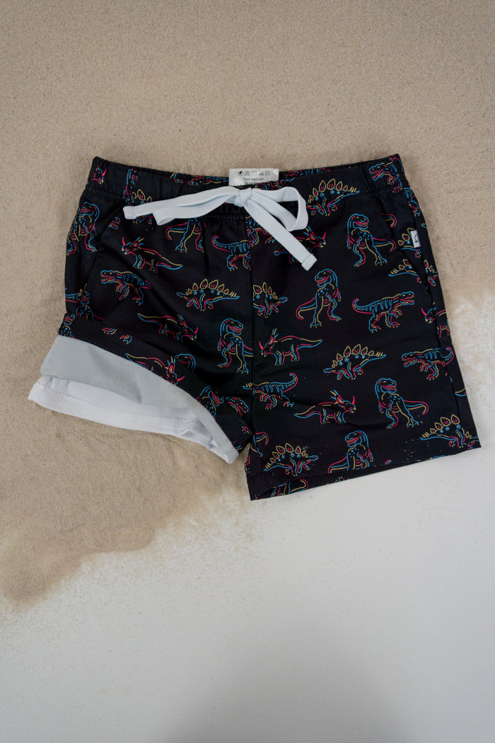 Black swim trunks with neon dinosaur outline pattern and white drawstring, white mesh lining visible at leg openings.