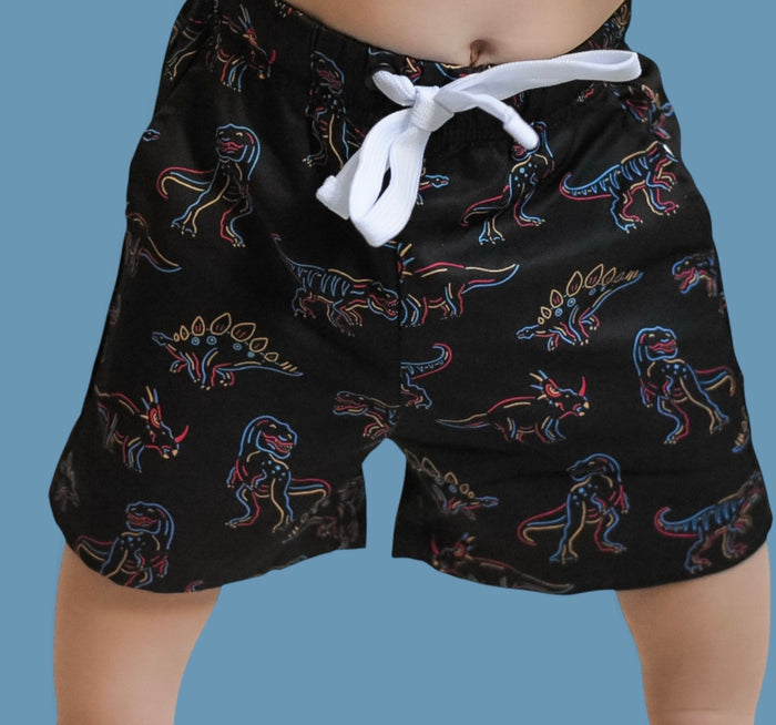 Black swim trunks with multicolored dinosaur print and white drawstring waistband.