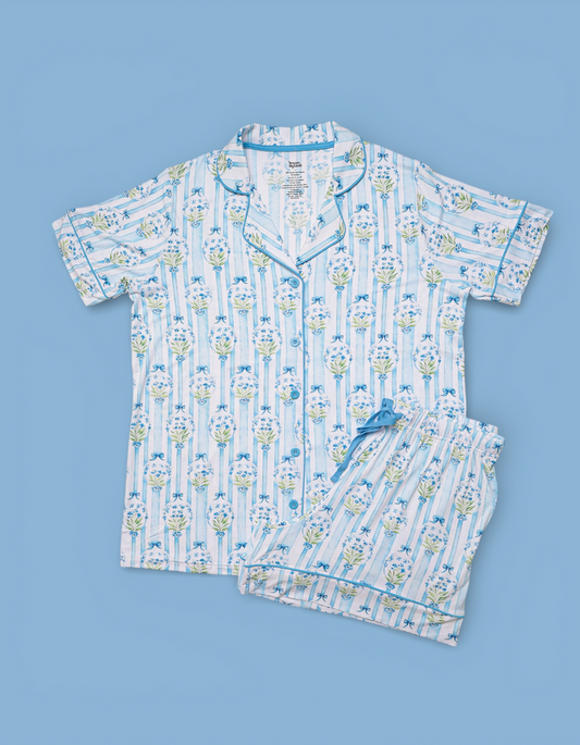 Two-piece women's pajama set with blue floral and striped print, short sleeve shirt and shorts, displayed flat on blue backgr
