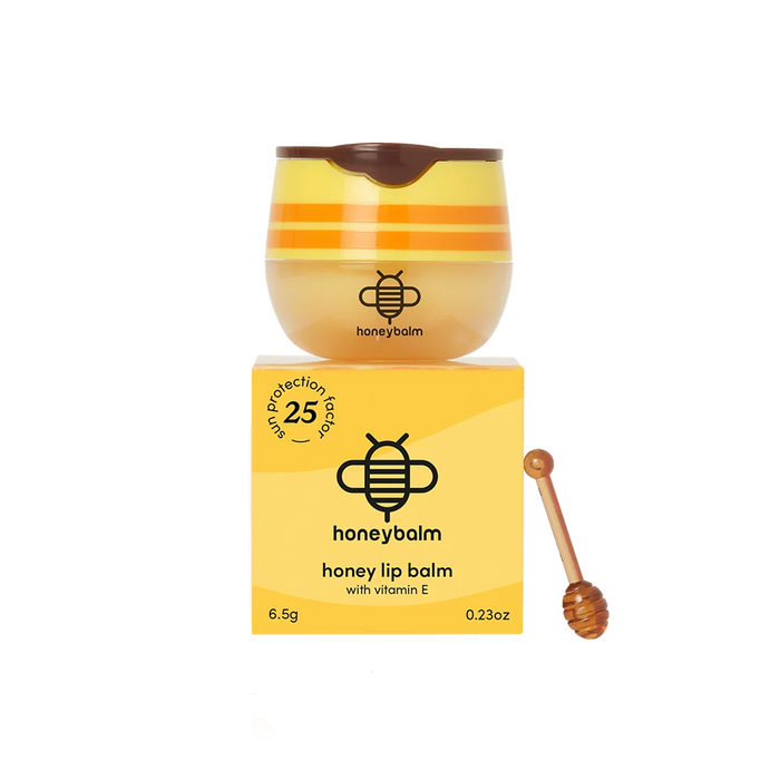 Honey lip balm with packaging and a wooden applicator on a white background