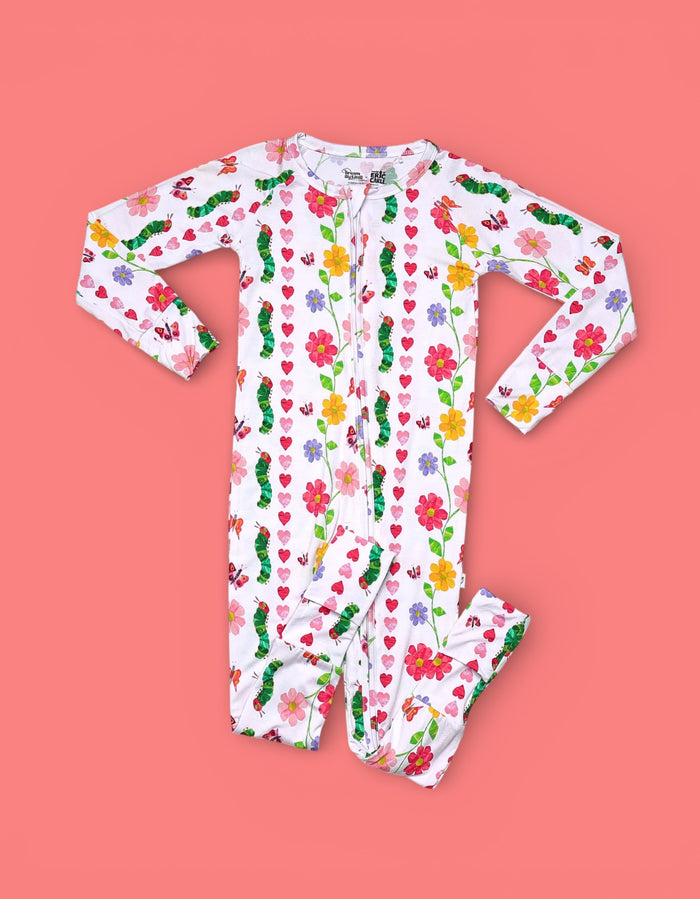 White long-sleeve romper with multicolored floral and heart print, front zip closure, and gathered cuffs.