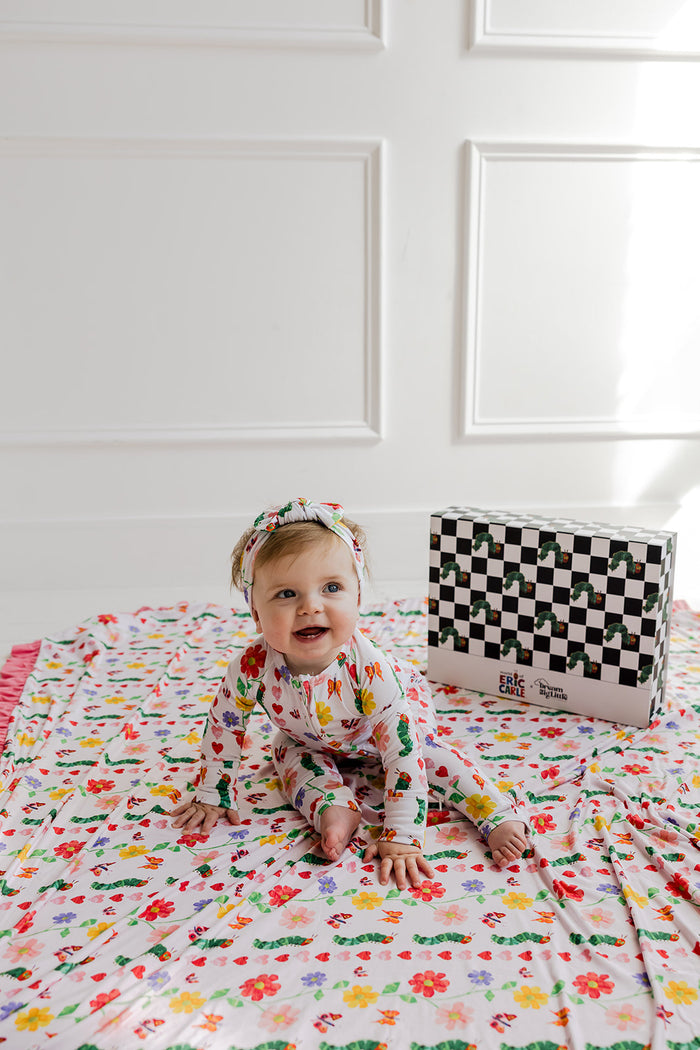 Infant romper in cream with multicolored floral and caterpillar print, long sleeves, paired with matching headband.