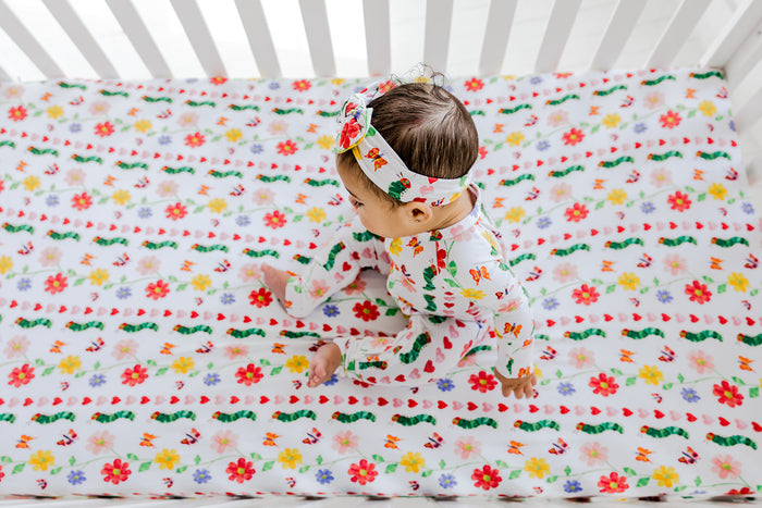 Infant romper with multicolored floral print and matching headband, shown on child from above.