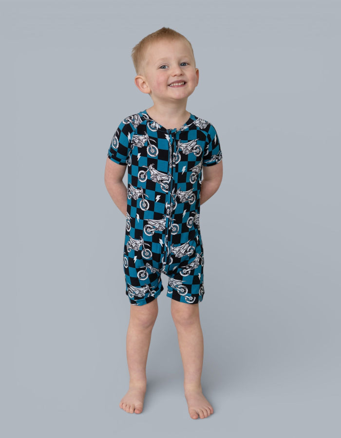 Toddler short-sleeved romper with teal and black diamond pattern featuring white motorcycle prints and front zipper closure.