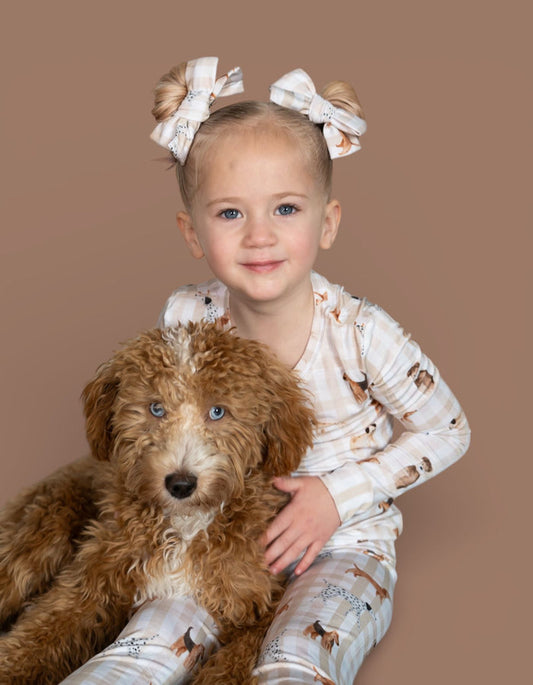 Pair of white bow hair clips with paw print details worn on top bun hairstyle.