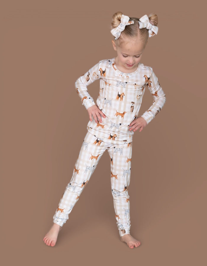 Pair of white bow hair clips with ruffled edges worn in child's hair on either side of head.