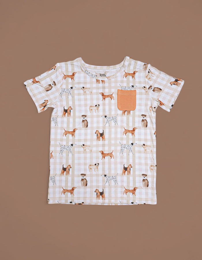 Short-sleeve tee with beige and white gingham pattern, multicolored dog print throughout, and orange chest pocket.