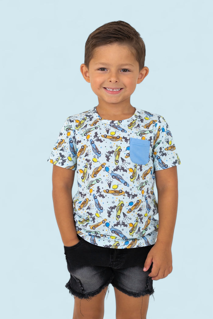 Boy's short-sleeve tee with racing car and checkered flag print, blue chest pocket, paired with black denim shorts.