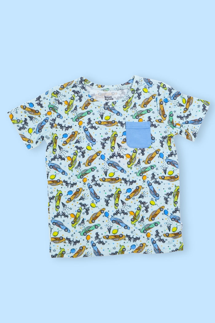 White short-sleeve t-shirt with blue chest pocket and all-over print of colorful racing cars, balloons, and stars.
