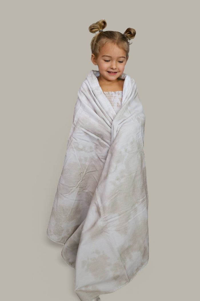 Young child wrapped in a light beige towel with a subtle textured pattern.