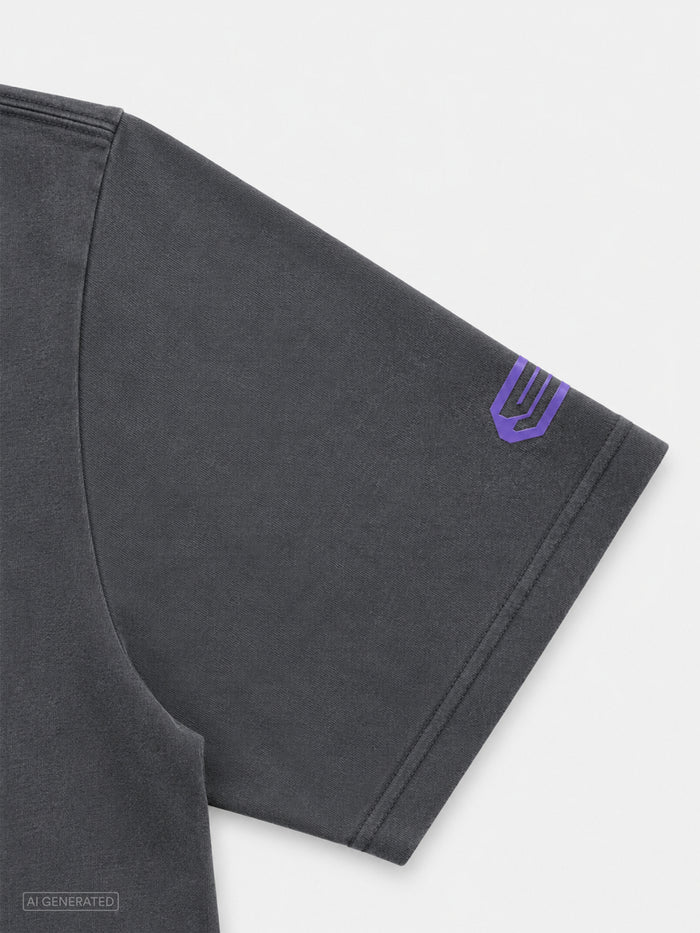 Detailaufnahme des rechten Ärmels eines dunkelgrauen T-Shirts. Nahe dem Ärmelabschluss befindet sich ein violettes Stone-Techno-Logo als kontrastierendes Designelement.